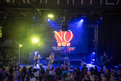 A No Doubt tribute band performing under neon stage lights to a packed crowd